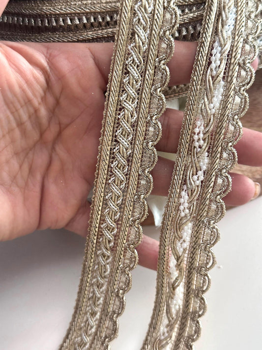 Elegant gold embroidered ribbons displayed on rolls for fabric embellishment.