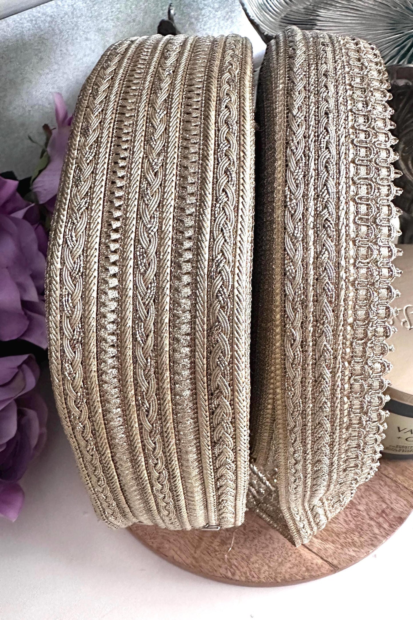 Close-up of gold metallic embroidered ribbon trim with intricate woven patterns.
Luxurious gold craft lace ribbon for sewing, wedding décor, and DIY projects.
