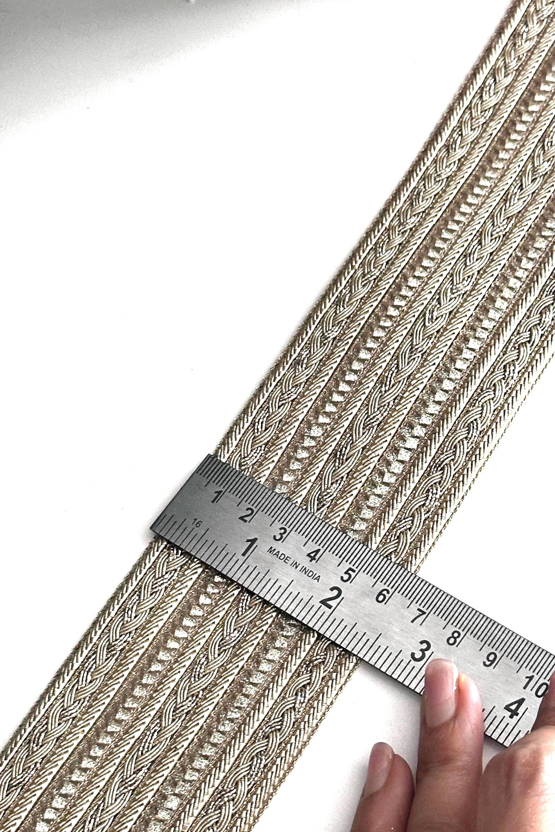 Shimmering gold metallic trim displayed on fabric rolls for crafting and design.