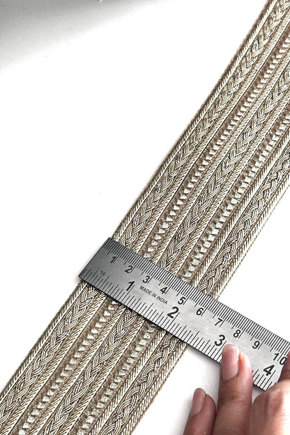 Shimmering gold metallic trim displayed on fabric rolls for crafting and design.
