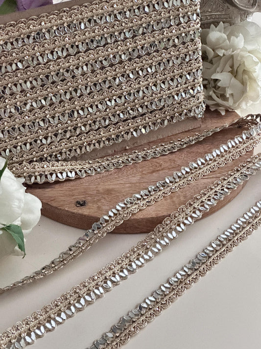Close-up of golden mirror trim with braided design, ideal for saree borders, wedding dresses, and luxury fashion embellishments.