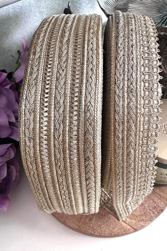 Close-up of gold metallic embroidered ribbon trim with intricate woven patterns.
Luxurious gold craft lace ribbon for sewing, wedding décor, and DIY projects.