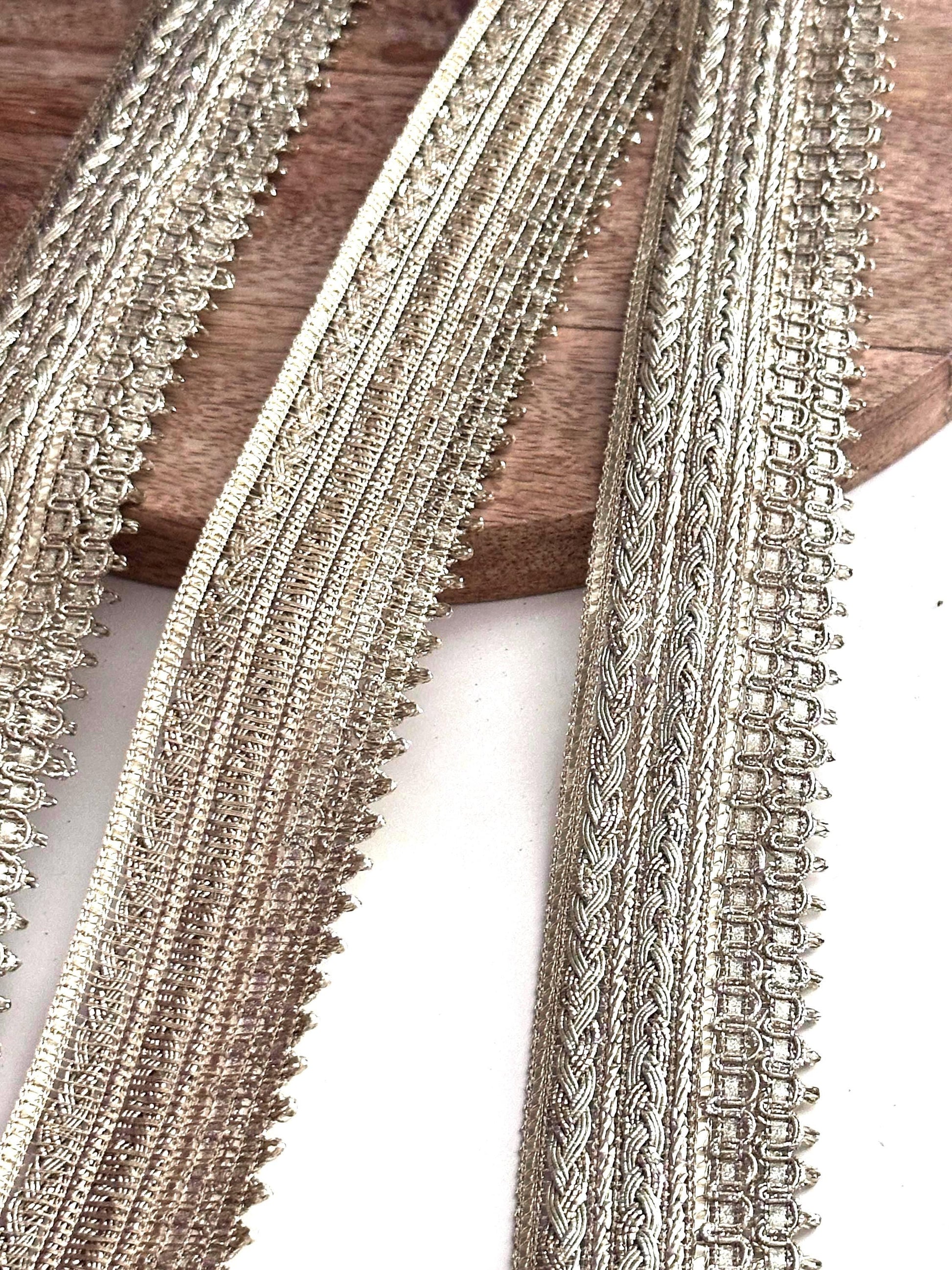 Close-up of gold metallic embroidered ribbon trim with intricate woven patterns.
Luxurious gold craft lace ribbon for sewing, wedding décor, and DIY projects.
High-quality metallic thread trim for bridal gowns, ethnic wear, and accessories.
